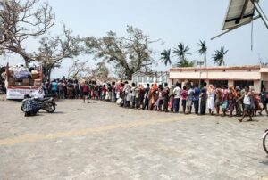 Long queue amidst the battered trees.