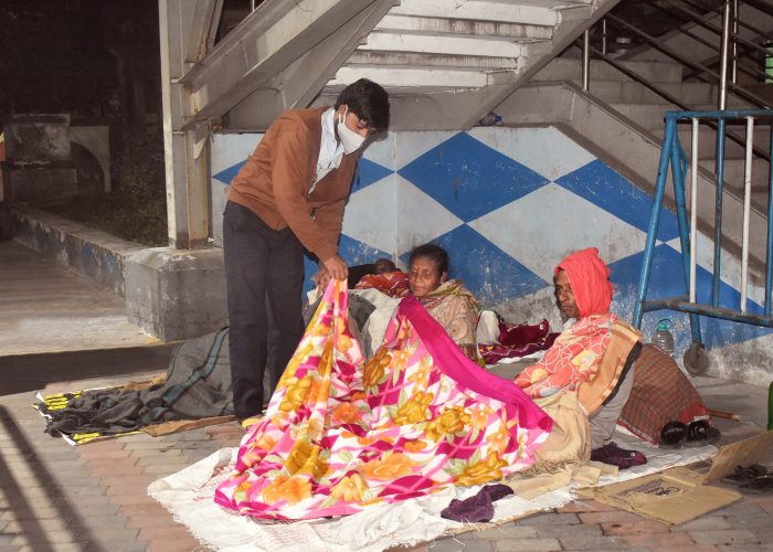 Dak Support Seva Activity 2021 A volunteer distributes blankets at Dakshineswar station.